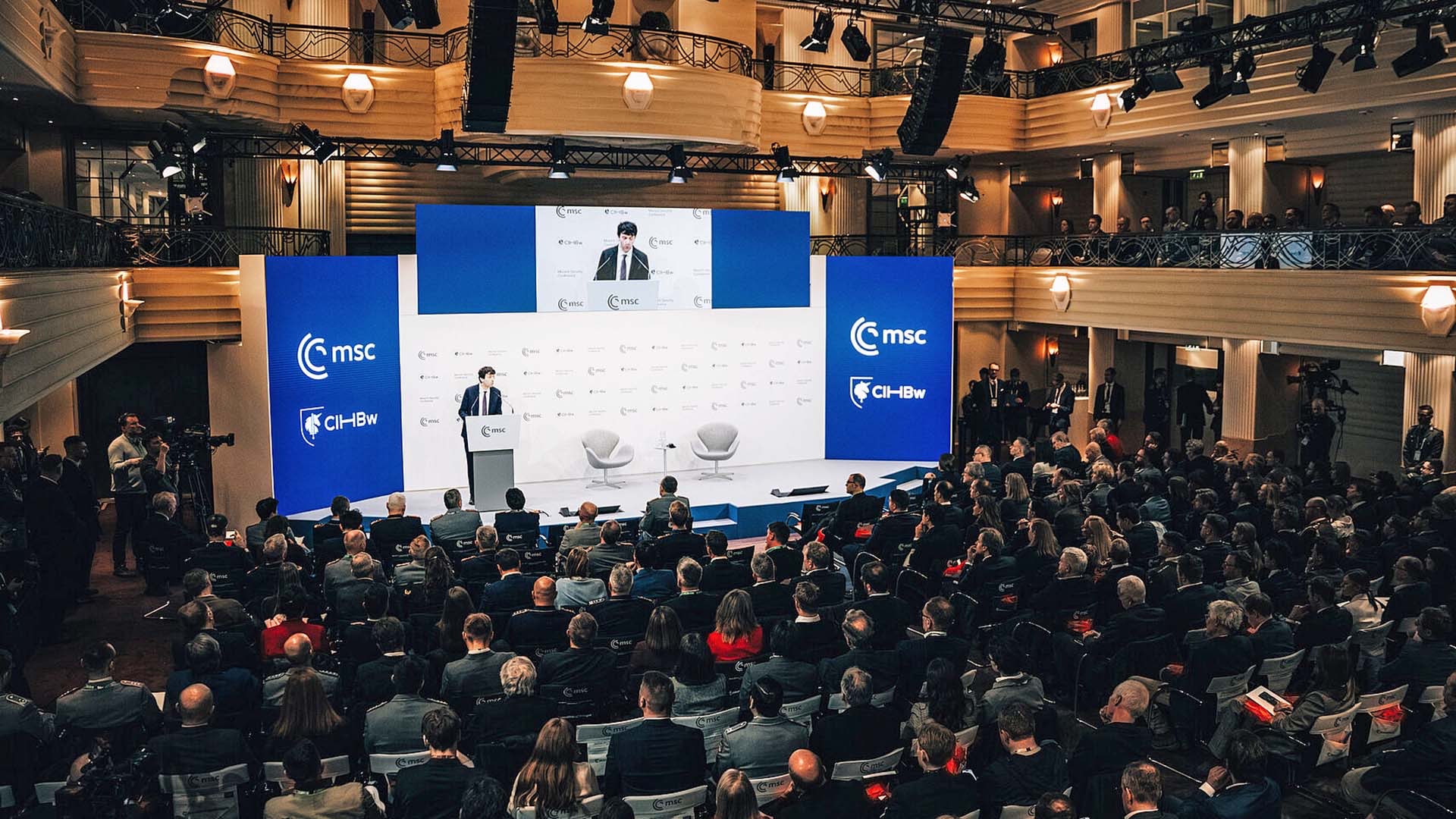 Großer Konferenzsaal mit Bühne, Publikum und Präsentationsscreen