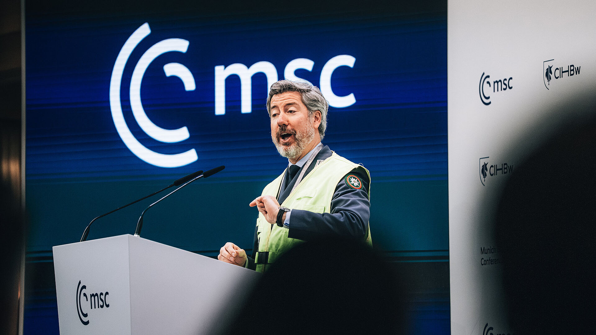 Person spricht am Rednerpult vor Bildschirm mit MSC‑Logo