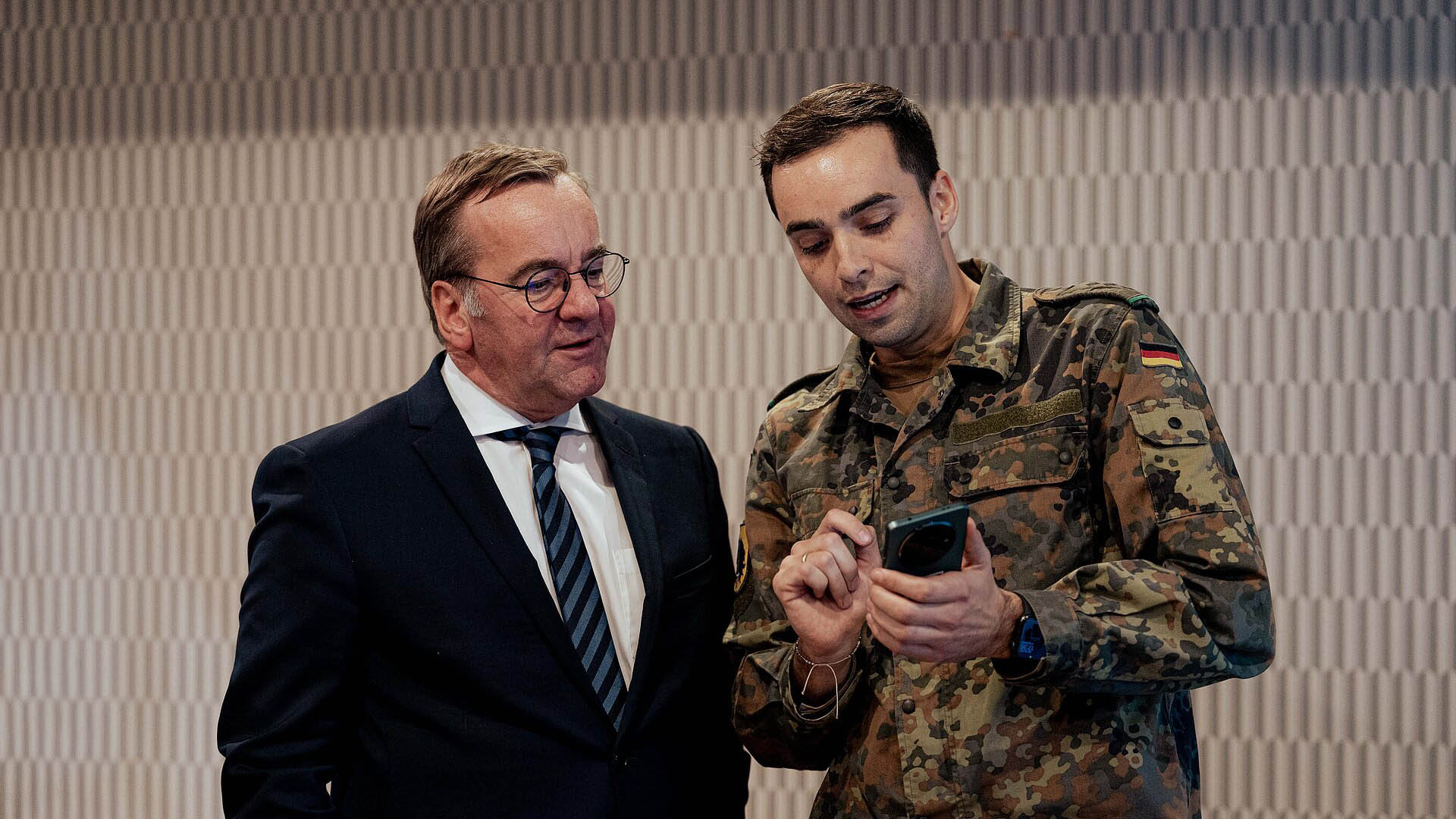 Person in Uniform zeigt Pistorius etwas auf Smartphone 