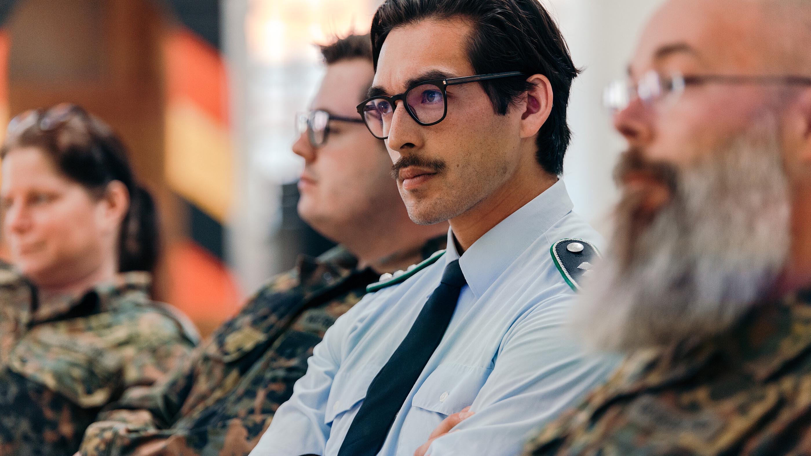 Teilnehmende in Uniform sitzen aufmerksam bei Veranstaltung