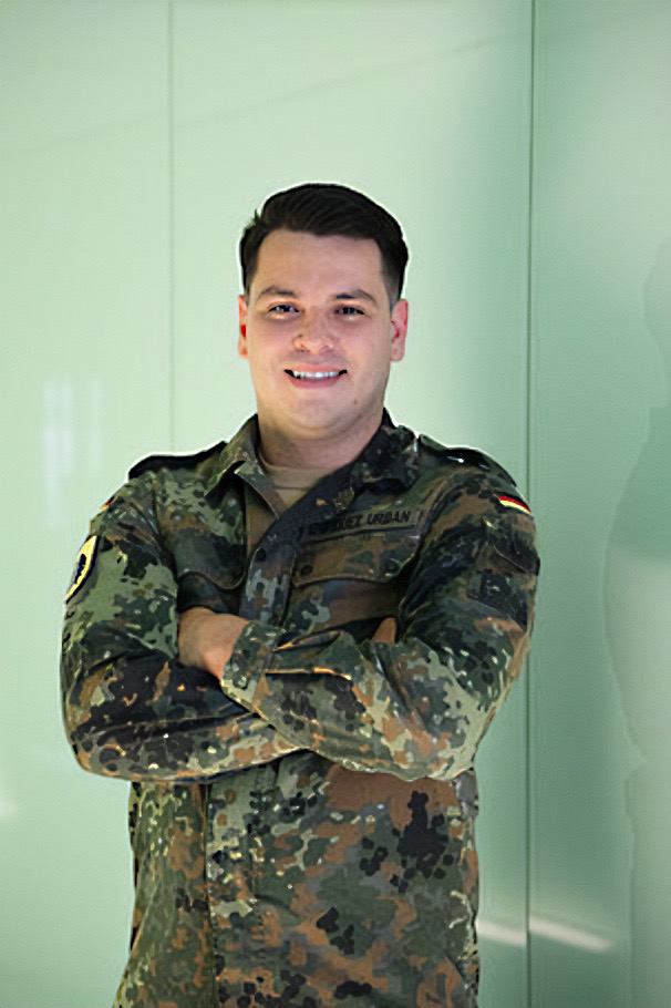 Leutnant Christopher steht in Uniform mit verschränkten Armen vor hellem Hintergrund