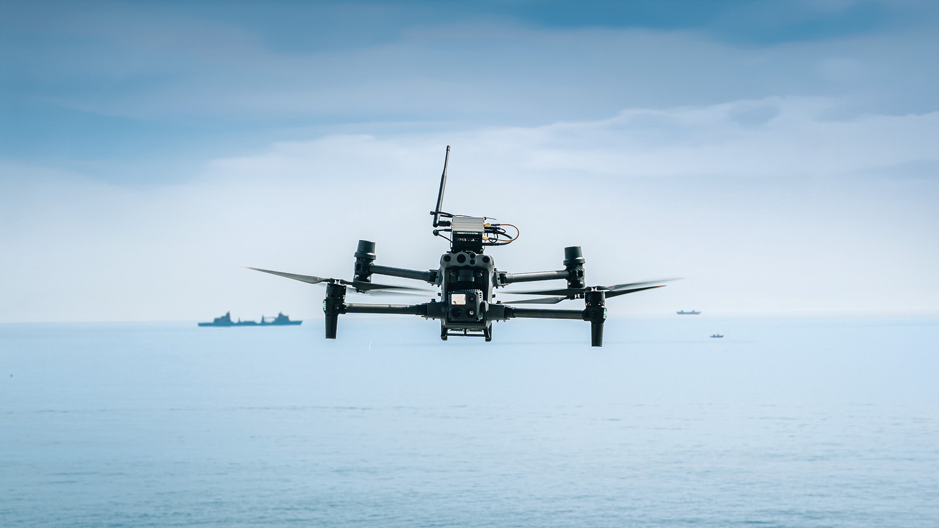 Drohne fliegt über Wasser mit Schiffen im Hintergrund