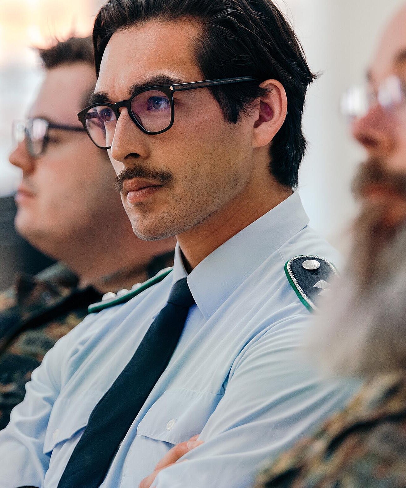 Teilnehmende in Uniform sitzen aufmerksam bei Veranstaltung