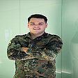 Leutnant Christopher steht in Uniform mit verschränkten Armen vor hellem Hintergrund