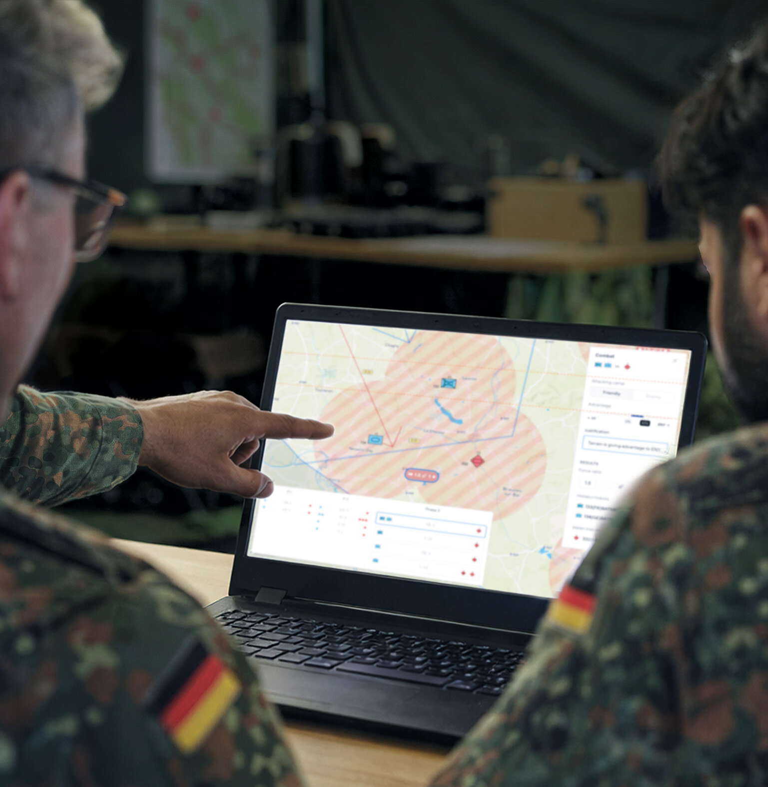 Zwei Soldaten analysieren digitale Lagekarte auf Laptop
