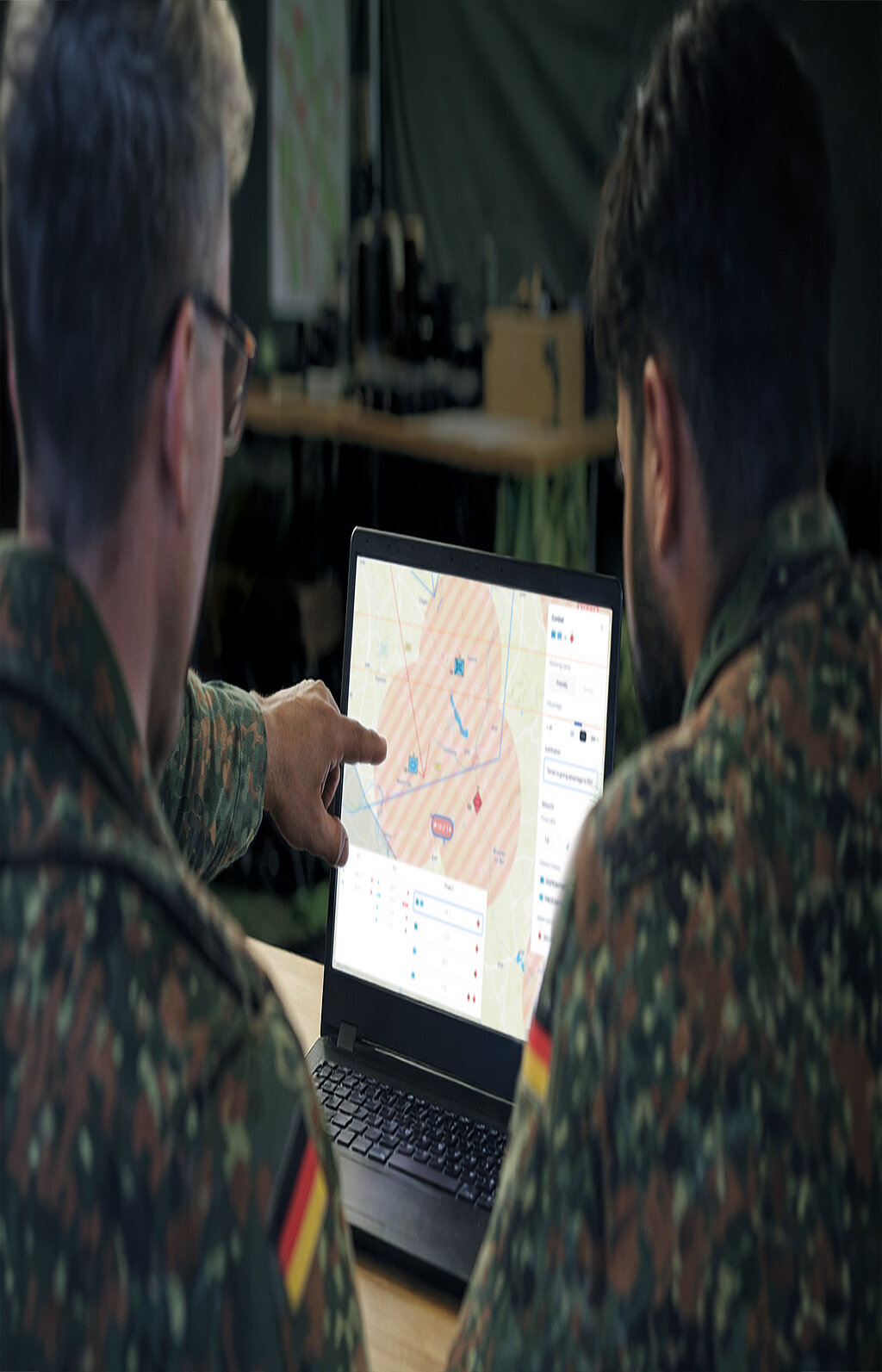 Zwei Soldaten analysieren digitale Lagekarte auf Laptop
