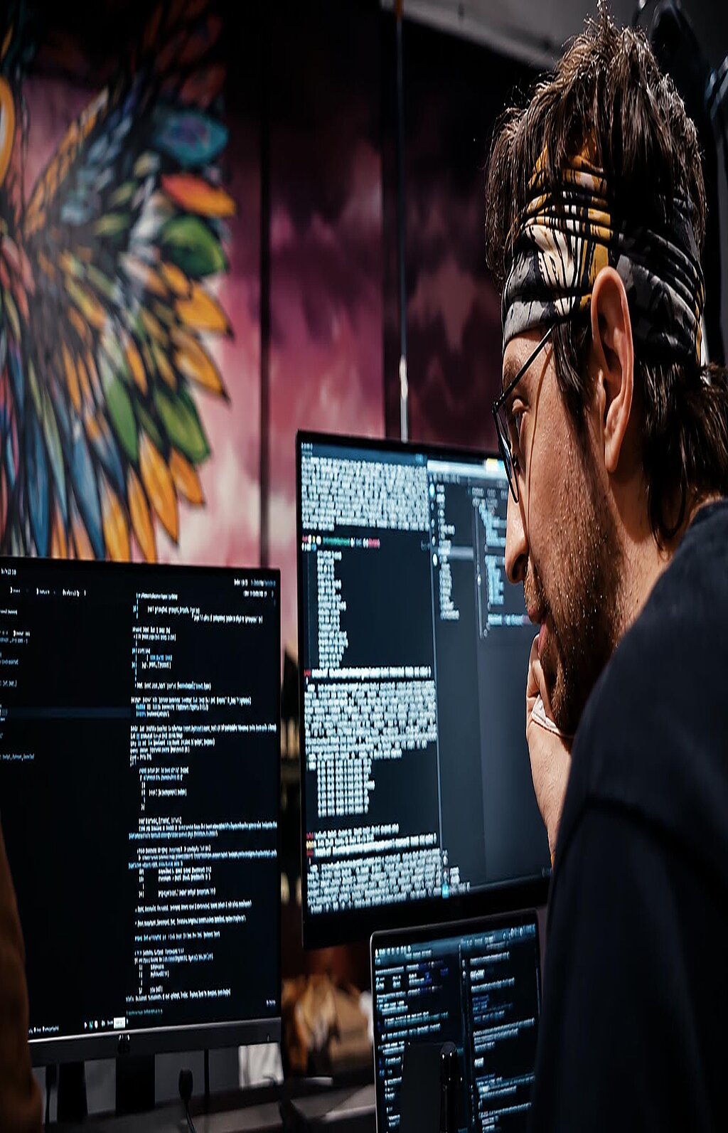 Person arbeitet an mehreren Monitoren mit Code