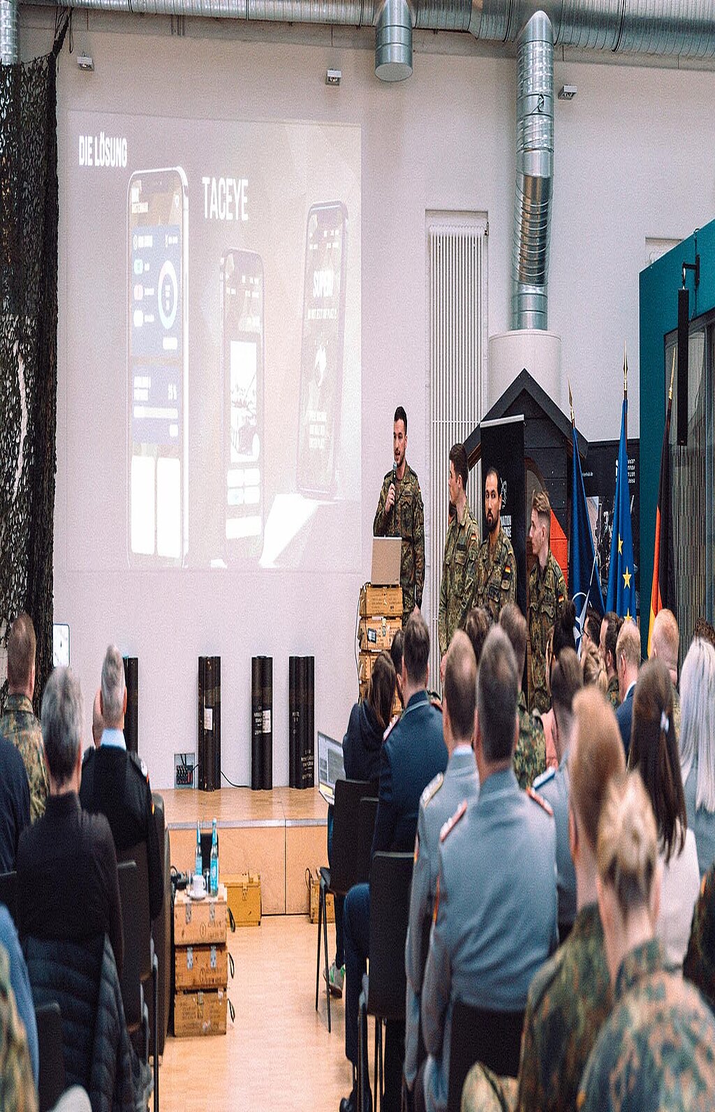 Mehrere Soldaten präsentieren Projekt vor Publikum und Bildschirm