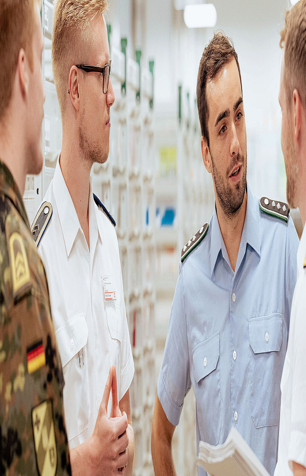 Mehrere Soldaten und zivile Personen besprechen Inhalte in technischem Raum