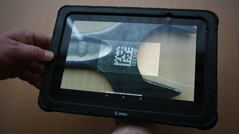 Tablet is held over a tool. It is scanned via a QR code.