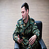 Christian Wendland sitzt in Uniform in Sessel und hält Smartphone im Gespräch