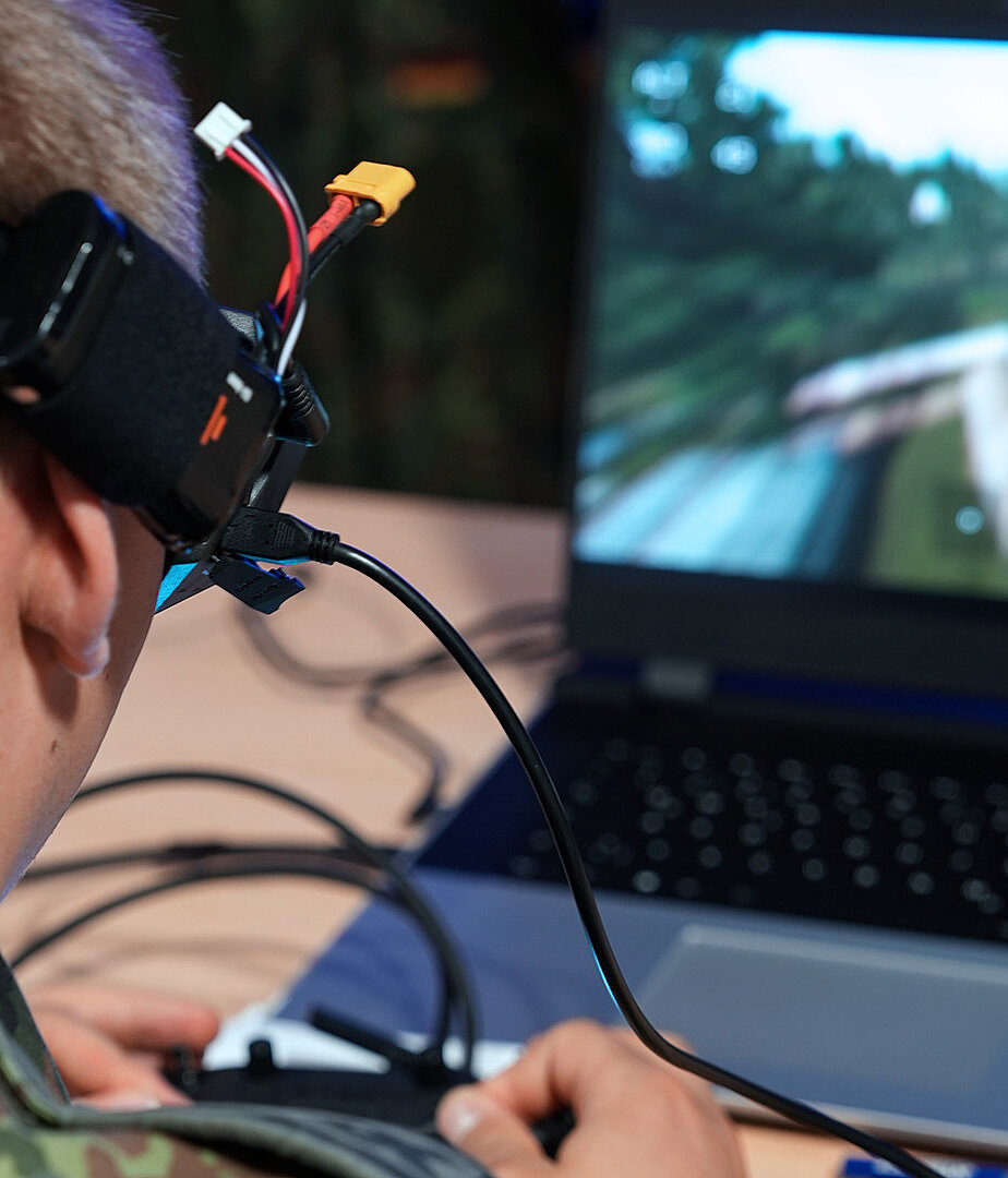 Person trägt VR-Brille und steuert Simulation vor Laptop