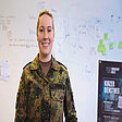 Hauptmann Anna Thumer in Uniform steht lächelnd vor Whiteboard mit Skizzen