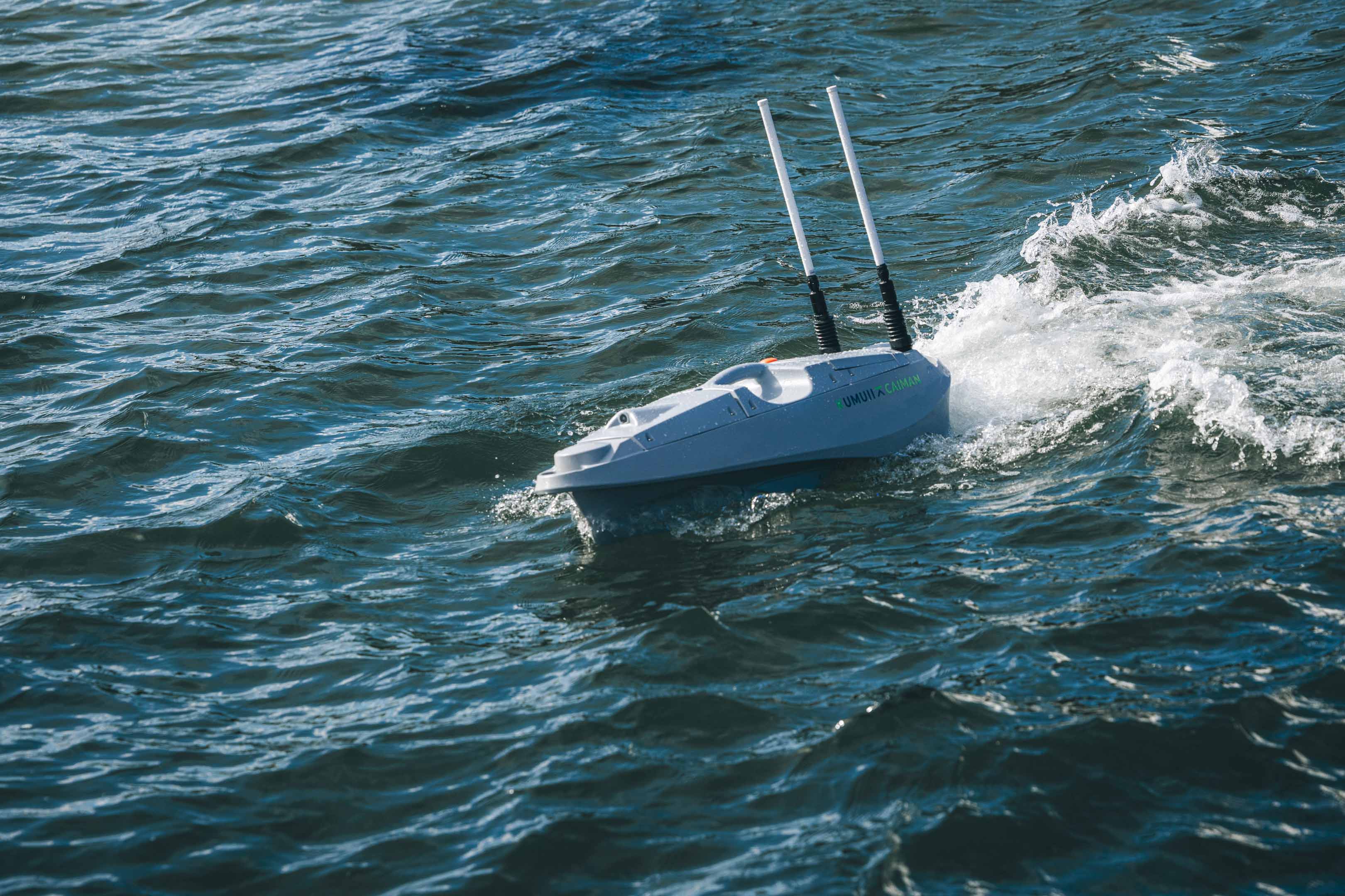 Auf dem Meer fährt ein unbemanntes Wasserfahrzeug mit zwei Antennen eine Kurve.