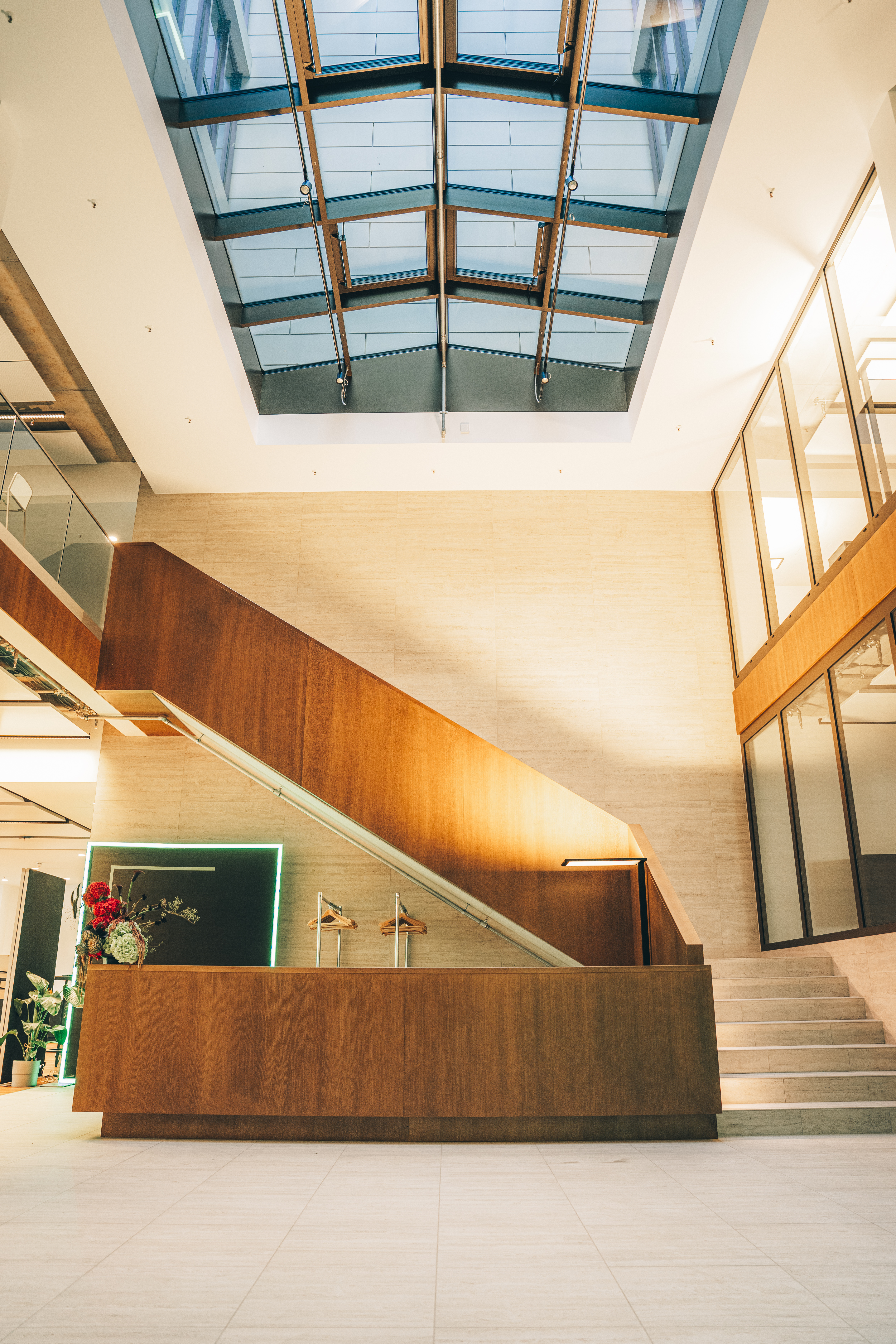 Hell erleuchtetes, offenes Treppenhaus im Eventbereich des Bürogebäudes am Schöneberger Ufer mit Empfangstresen und eine Glaskuppel.