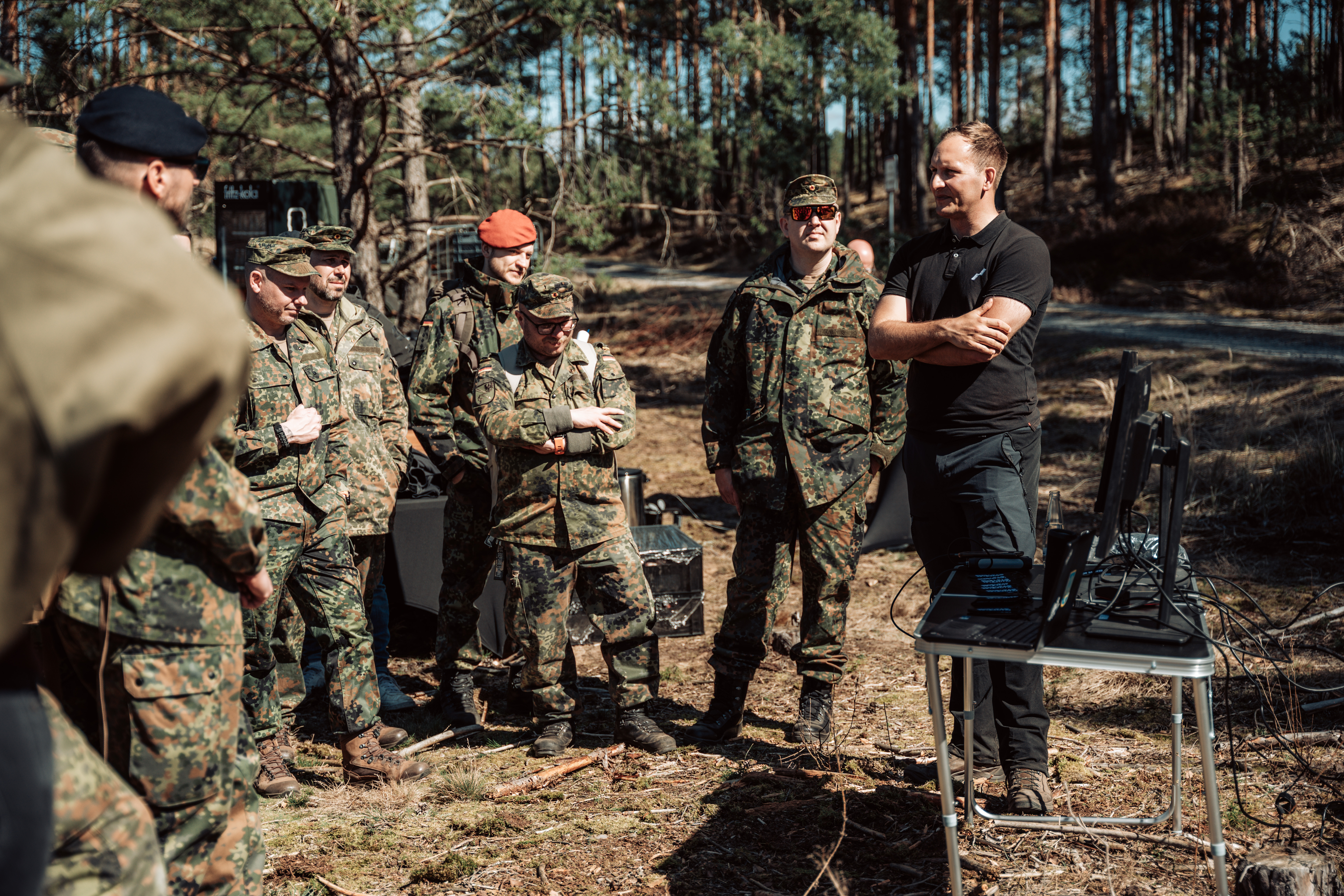 Soldaten und Zivilisten stehen im Wald und reden.